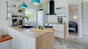 A modern kitchen with white cabinetry, a wooden island, and blue pendant lights. - "Liutulf" - 40m from the sea by Interhome (Haderslev)