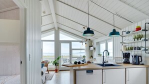A modern kitchen with a central island, pendant lights, and a view of the sea. - "Liutulf" - 40m from the sea by Interhome (Haderslev)