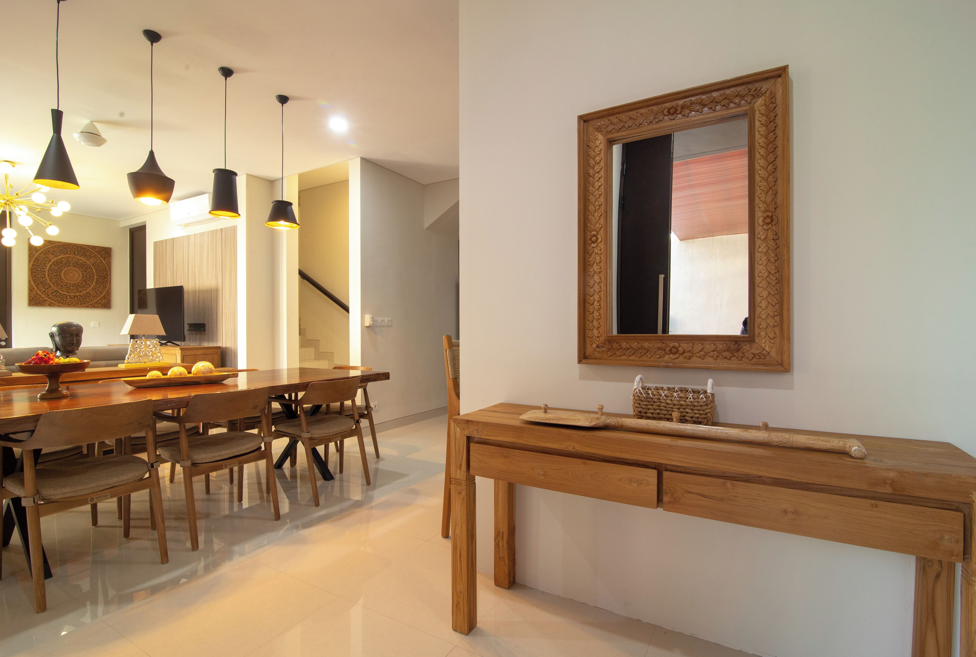 A dining area with a wooden table and chairs, pendant lights, and a decorative mirror on the wall.