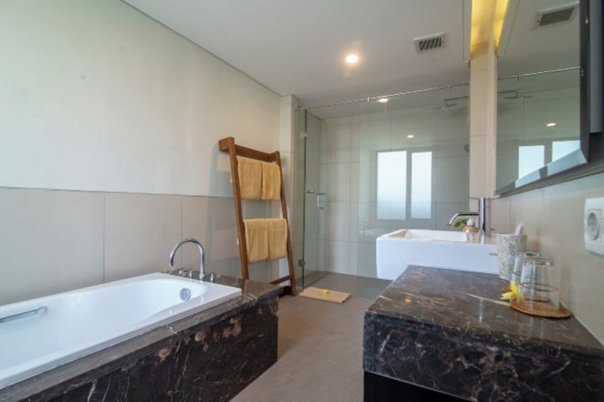 Un baño moderno con una bañera grande, zona de ducha separada y tocador con espejo.