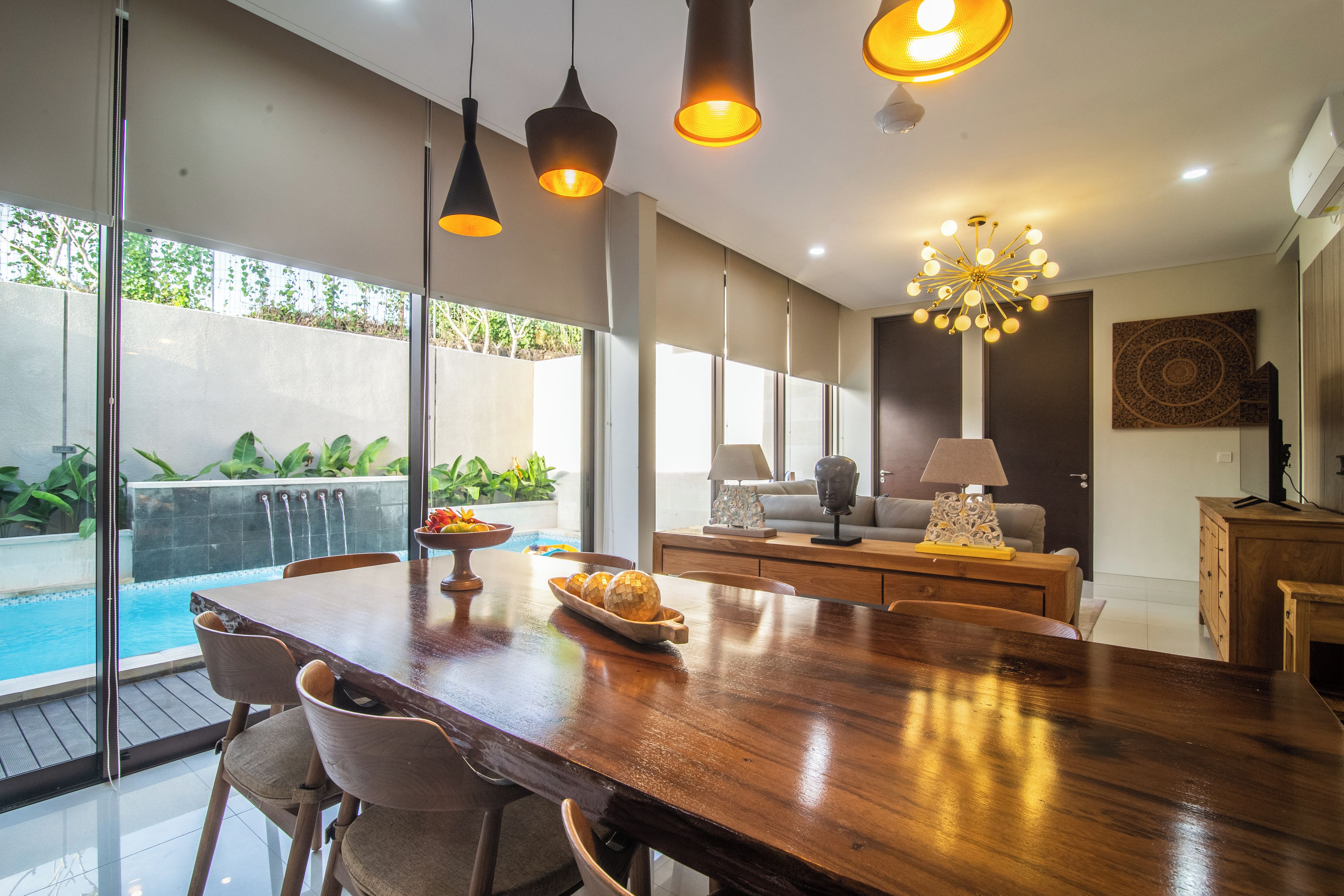 A spacious dining area with a wooden table, chairs, and pendant lighting.