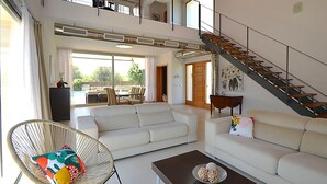 A spacious living room with a high ceiling, a staircase, and a balcony. - Vacation home Caleu by Interhome (Binissalem)