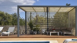 A poolside area with a covered seating area, lounge chairs, and a small table with potted plants. - Vacation home Caleu by Interhome (Binissalem)