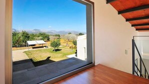 A modern room with a large sliding glass door leading to a balcony with a view of a vineyard and mountains. - Vacation home Caleu by Interhome (Binissalem)