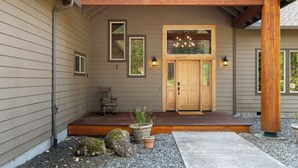 A wooden porch with a door, potted plants, and a bench. - 4000sqft, 1-acre Custom Cabin Retreat w Game Room, Hot Tub & Sauna @Mt Hood (Rhododendron)