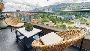 A balcony with wicker chairs, a table, and a potted plant. - Luxury Duplex, Poblado Gem!
 (Medellín)