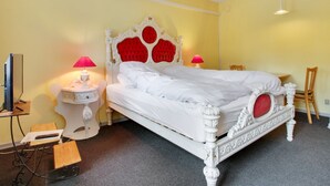 A white four-poster bed with red headboard and footboard, two bedside tables with lamps, a chair, a desk with a computer, and an air conditioning unit on the wall. - "Gunhild" - 22km from the sea by Interhome (Bredebro)