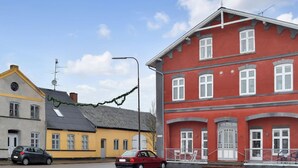 A street view with a red building, a yellow building, and a grey building. There are two cars parked on the street. - "Gunhild" - 22km from the sea by Interhome (Bredebro)