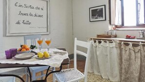 Un comedor con una mesa preparada para dos, una cita enmarcadas en la pared y una ventana con cortinas.