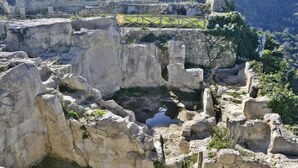 Ruinas antiguas con estructuras de piedra y un pequeño estanque.