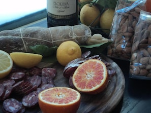 Una variedad de alimentos como salami en rodajas, naranjas y almendras sobre una tabla de madera.