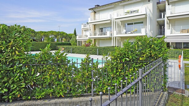 A multi-story hotel with balconies, a swimming pool, and lush greenery. - La Castellana Relax in Sirmione (Sirmione)