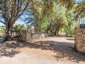 A gravel pathway leading to a gated entrance with a stone wall and metal gate.