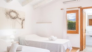 Ein Zimmer mit zwei Betten, einer Holzbalkendecke, einem Gemälde und einem Badezimmer mit Fenster.