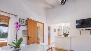 Eine moderne Küche mit Fernseher, ein Essbereich mit Tisch und Stühlen sowie Blick ins Freie.