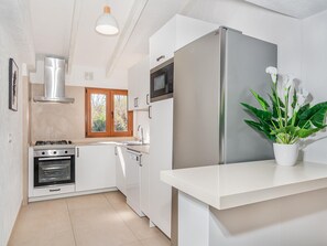 A modern kitchen with white cabinetry, a stainless steel refrigerator, a built-in oven, and a microwave.