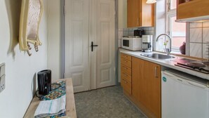 Une cuisine compacte dotée de meubles en bois, d’un four à micro-ondes, d’une machine à café et d’un lave-vaisselle Samsung.