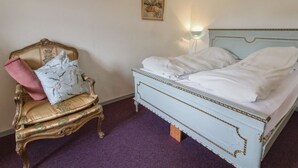 Une chambre à coucher comprenant un lit, une chaise et deux tableaux accrochés au mur.