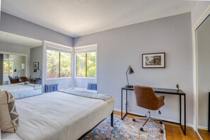 Relax in this serene bedroom with a large bed, desk, and comfortable chair, perfect for working or unwinding.