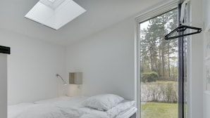 A bedroom with a skylight, a bed, a bedside table with a lamp, and a view of a garden through a sliding door. - "Wehrhart" - 200m from the sea by Interhome (Væggerløse)