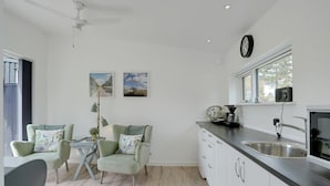 A modern kitchen with white cabinets, a dark countertop, and a built-in oven. There is a dining area with two chairs and a table, and a ceiling fan. - "Wehrhart" - 200m from the sea by Interhome (Væggerløse)