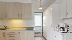 Une cuisine moderne avec des meubles de couleur bois clair, un plan de travail en granit, une machine à café et un four encastré.
