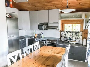 Cozinha compacta com uma mesa de jantar de madeira, geladeira, micro-ondas e fogão.