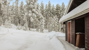 Un sentier enneigé mène à un bâtiment dont l’extérieur est en bois et dont la porte est rouge.