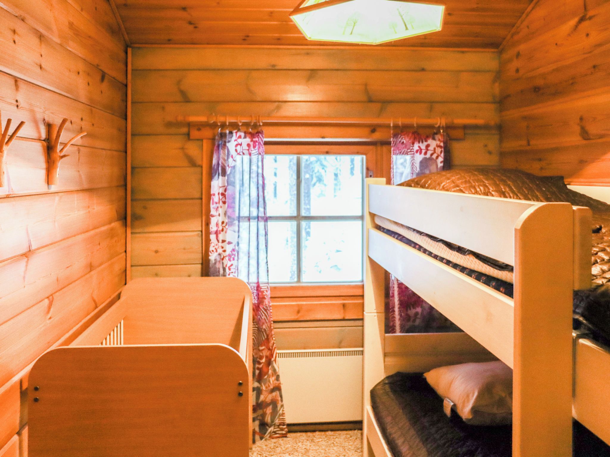 Una cabaña con literas, un escritorio pequeño y una ventana con cortinas.