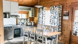 Une cuisine aménagée dans un style rustique, avec une table et des chaises, des murs en bois et une fenêtre avec des rideaux.