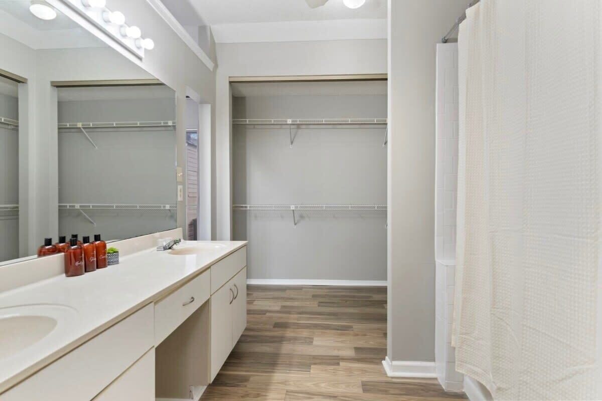 Un baño moderno con tocador, espejo y zona de ducha.