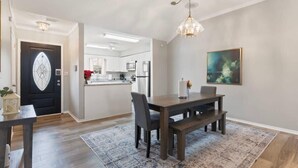 Une cuisine moderne avec des meubles blancs, un îlot central et un coin repas comprenant une table et un banc en bois.