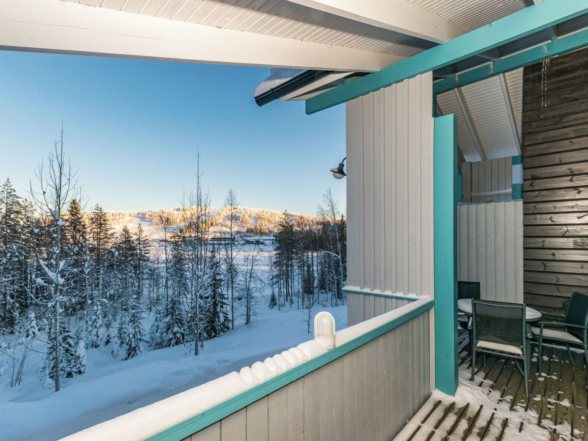 A balcony with a view of a snowy landscape and a wooden wall.