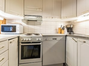 A kitchen with white cabinets, a microwave, a stove, a dishwasher, and a coffee maker. - Rakotuli 2 paritalon yläkerta by Interhome (Hyrynsalmi)