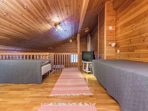 A cabin with two beds, a television, and a wooden ceiling. - Rakotuli 2 paritalon yläkerta by Interhome (Hyrynsalmi)