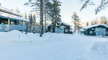 A snow-covered landscape with a cabin and a building with a blue exterior.