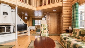 A log cabin interior with a wooden staircase, a fireplace, a television, a sofa, and a dining area. - Aurinkoinen hirsimökki by Interhome (Hyrynsalmi)