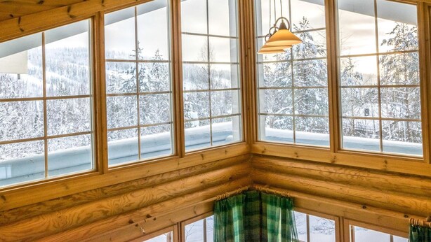 A corner room with large windows, wooden ceiling, and a hanging light fixture. - Aurinkoinen hirsimökki by Interhome (Hyrynsalmi)
