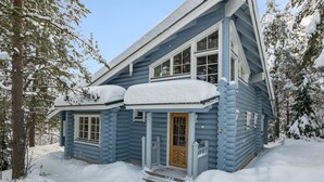 A log cabin with a wooden door and windows, surrounded by snow-covered trees. - Aurinkoinen hirsimökki by Interhome (Hyrynsalmi)