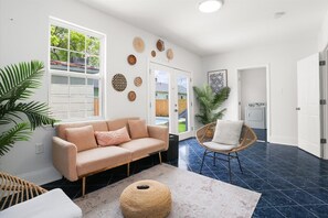 Ein Wohnzimmer mit Sofa, Sessel, Teppich und Wanddekoration.