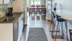 A modern kitchen with a built-in microwave, a coffee maker, and a dining area with a table and chairs. - Skivillas 47 ukkohalla (a1) by Interhome (Hyrynsalmi)
