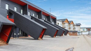 A row of modern, multi-story buildings with red accents and a clear sky. - Skivillas 47 ukkohalla (a1) by Interhome (Hyrynsalmi)