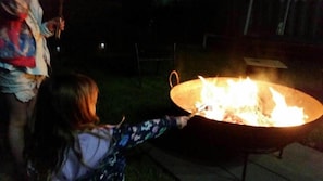 A person tending to a fire in a metal fire pit outdoors at night. - The Wharf House @ Sussex Inlet (Sussex Inlet)