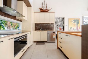 A modern kitchen with a built-in oven, a dishwasher, and a wooden ship decoration above the cabinets.