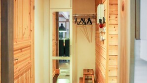 A narrow hallway with wooden walls and a door leading to a room with a bed and a nightstand.