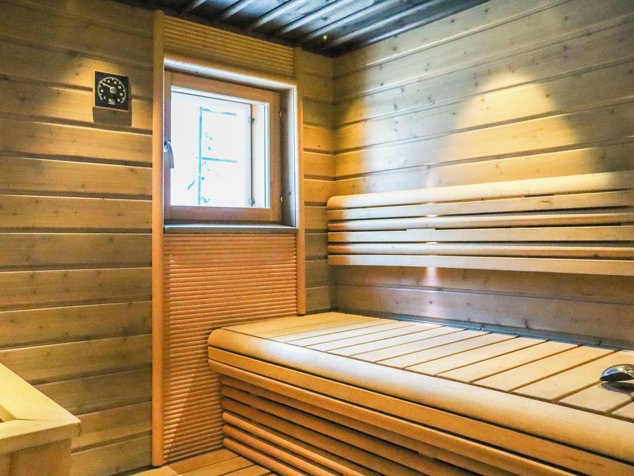 Un sauna con paredes de madera, un banco y una ventana.