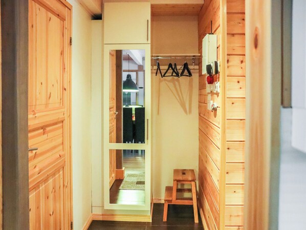 A narrow wooden hallway with a door leading to a room with a bed and a small table.