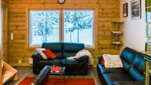 A cozy log cabin interior with two sofas, a coffee table, and a clock on the wall.
