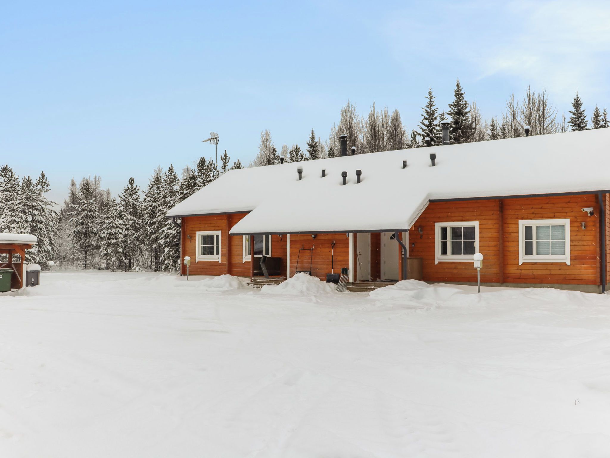 A wooden cabin with a snow-covered roof and a front porch.