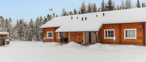 A wooden cabin with a snow-covered roof and a front porch.